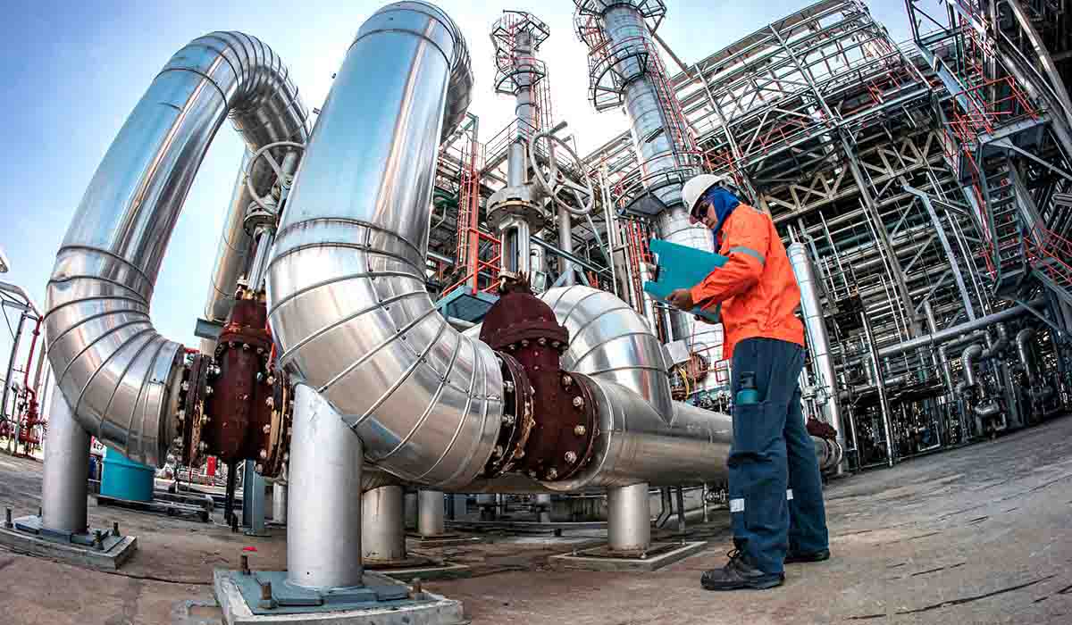 Male worker inspection at steel long pipes insulation and pipe elbow in station oil factory during refinery valve of visual check record pipeline